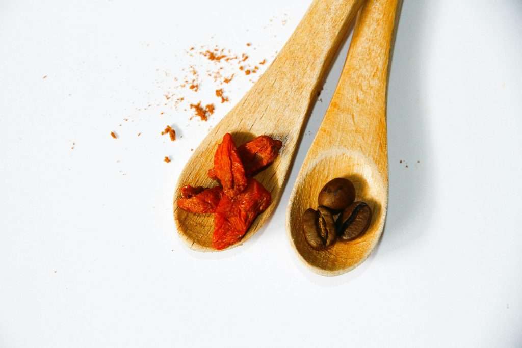 two wooden spoons with cayenne pepper and coffee beans.