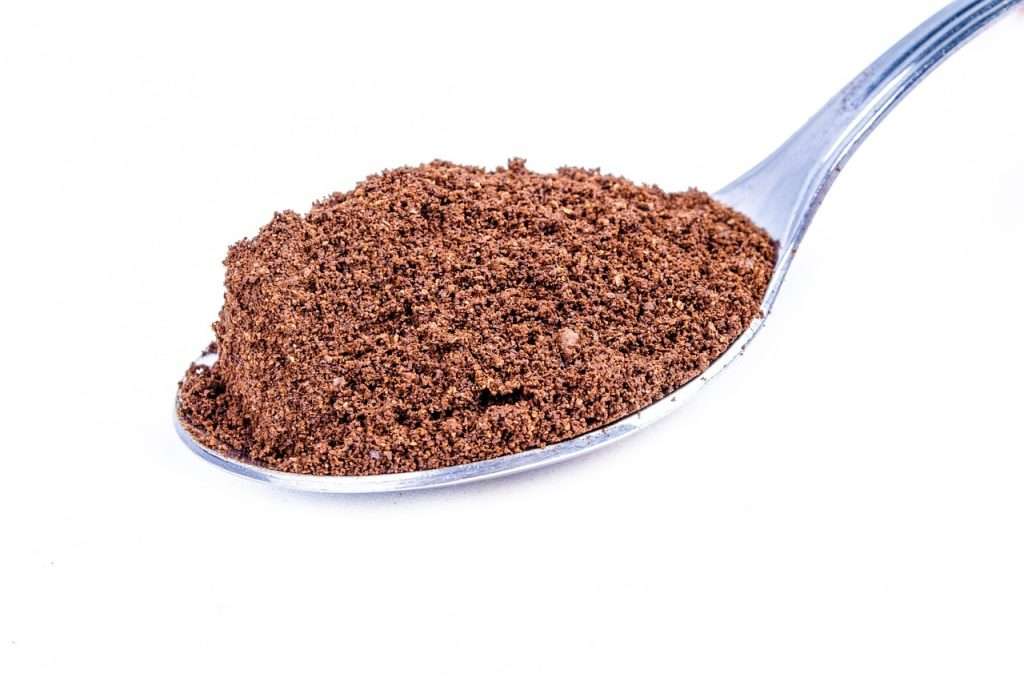 Scoop of finely ground instant coffee on white background.