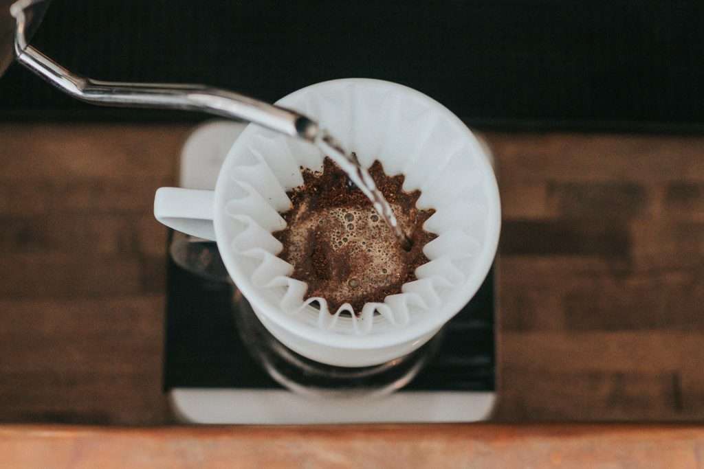 Pour-over coffee brewing in progress with a white paper filter placed on a ceramic cup.